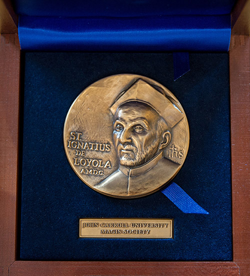 A medal resting in a wooden box, symbolizing achievement and recognition from the JCU Magis Society.