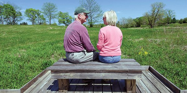A couple enjoying a peaceful moment together, sitting on a bench in a serene setting.